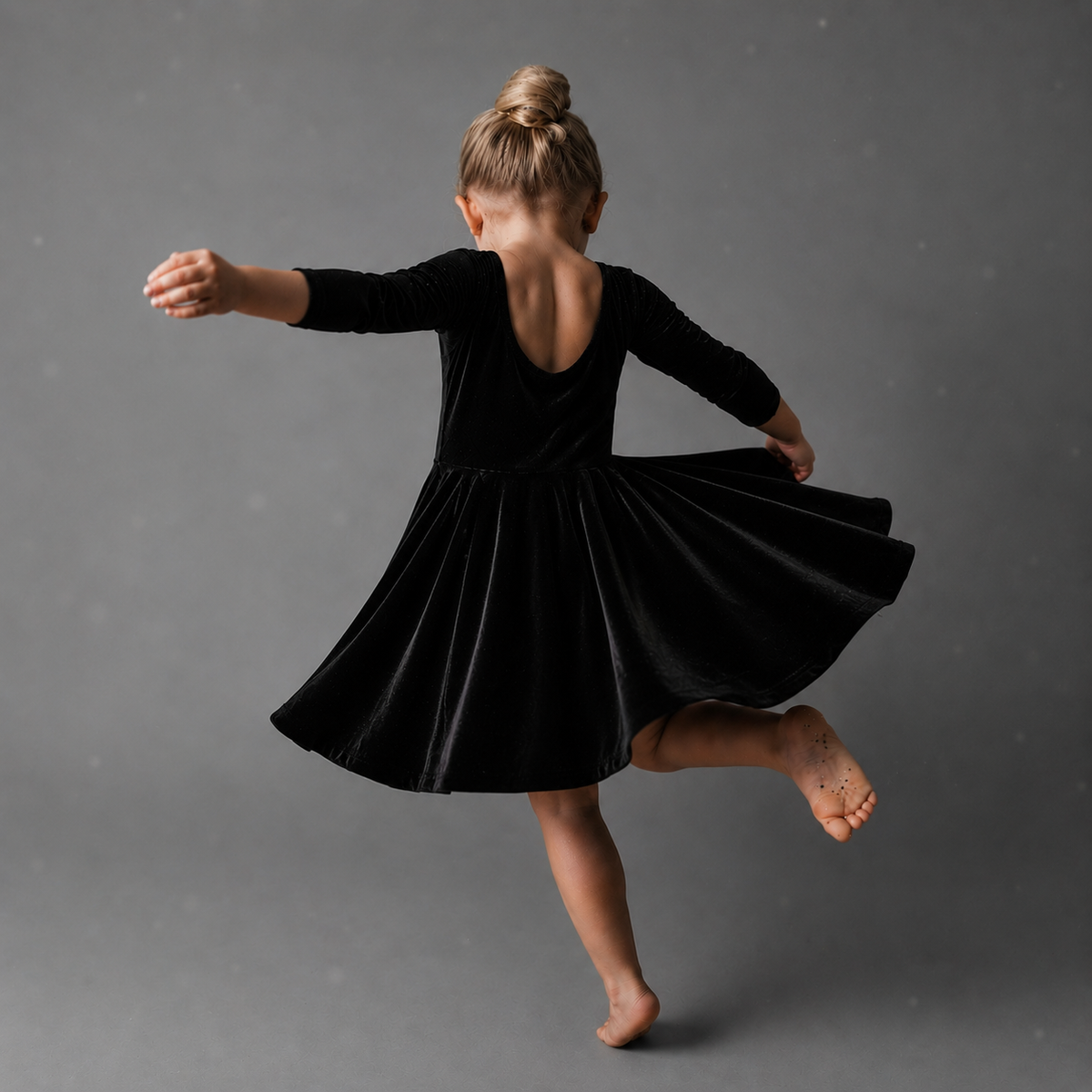 girl twirling in black velvet dress with 3/4 length sleeves