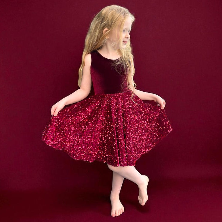 Young girl in a red sequin dress posing on a red background