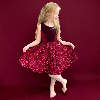 Young girl in a red sequin dress posing on a red background