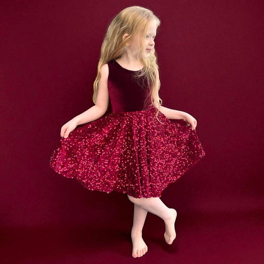 Young girl in a red sequin dress posing on a red background